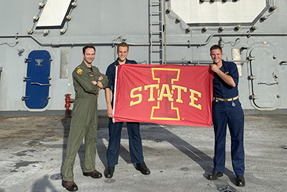 Navy Sailors on a ship holding an ISU flag